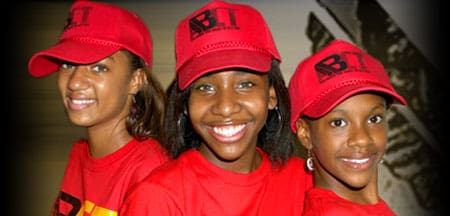 Three people wearing matching red hats and shirts with "ABI" printed on them, smiling at the camera.