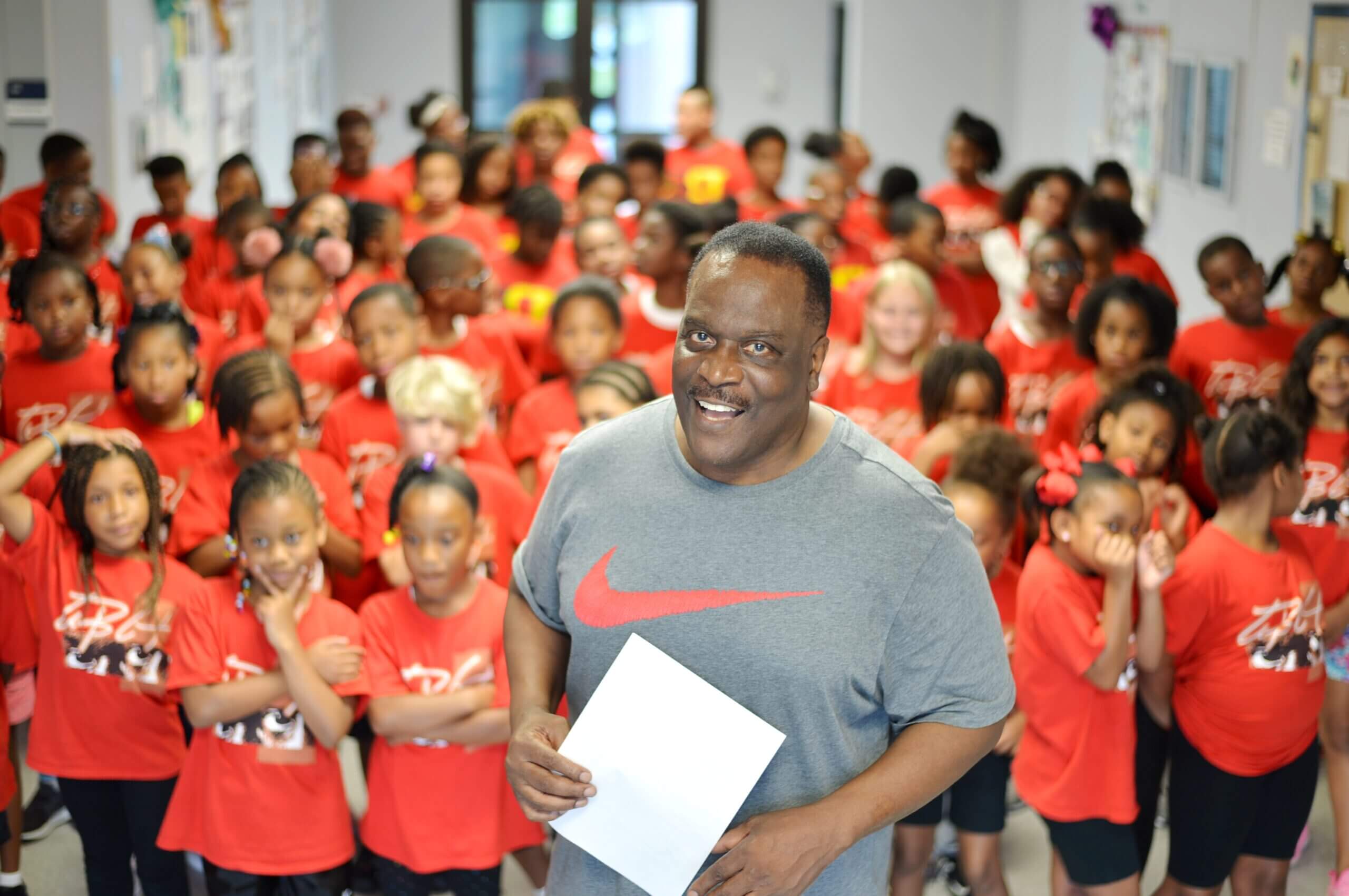 Man smiling in front of red-shirted children