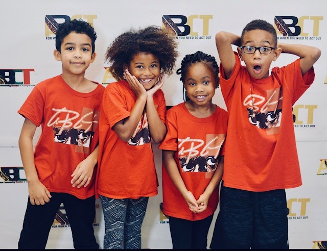 Four children in matching orange T-shirts posing