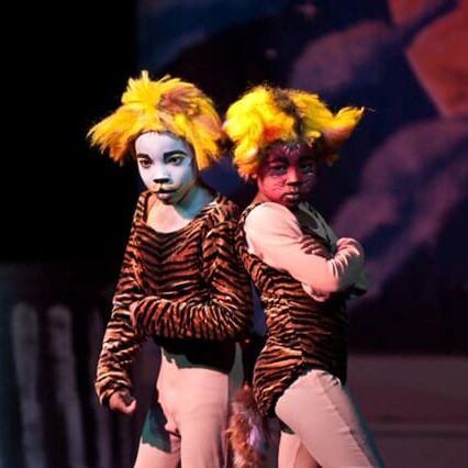 Two performers in striped tiger costumes on stage
